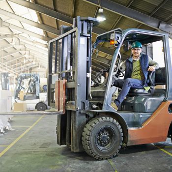 leiras-Portrait of driver in a forklift on the factory floor.