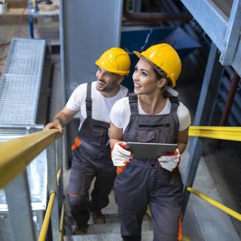 leiras-Industrial workers engineers walking in factory and climbing metal stairs.